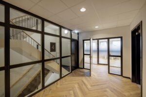 Modern hallway on the fourth floor of a building at Hiridostraat 3, featuring glass walls and a staircase.